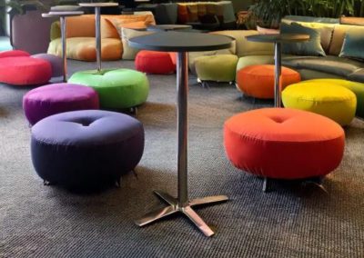 tavolino alto in alluminio per area lounge allestita con cuscini colorati